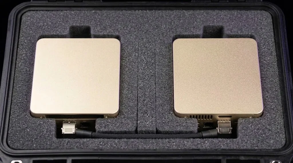 Product render: two compute nodes seated flush in cut foam inside the transit case, joined by one short direct-attach cable